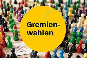 Spielfiguren in verschiedenen Farben stehen um ein Wahlkreuz herum